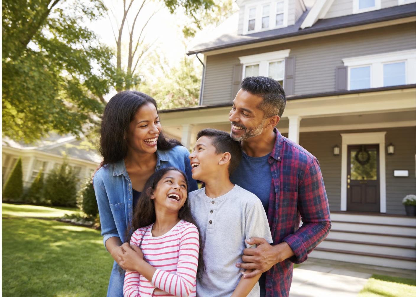 Family smiling in front of their home